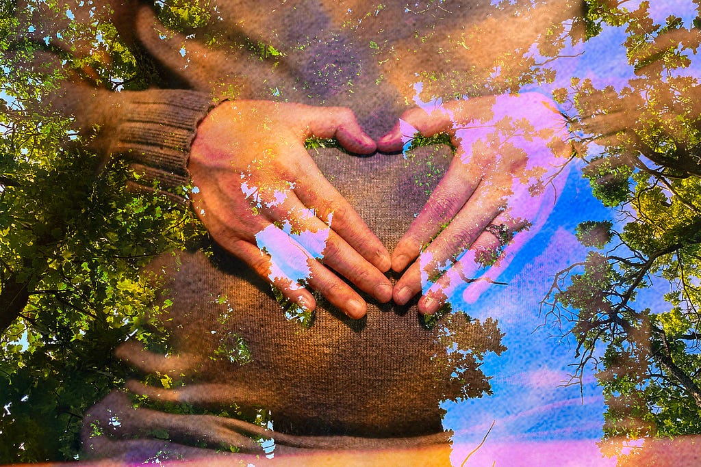 Woman showing heart symbol above her pregnant belly