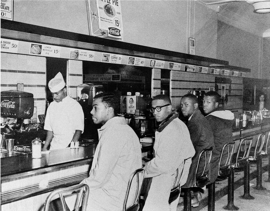 Picture of The Greensboro Four —  Joseph McNeil, Franklin McCain, Ezell Blair Jr., and David Richmond — sitting at the Woolworth’s lunch counter in Greensboro, North Carolina