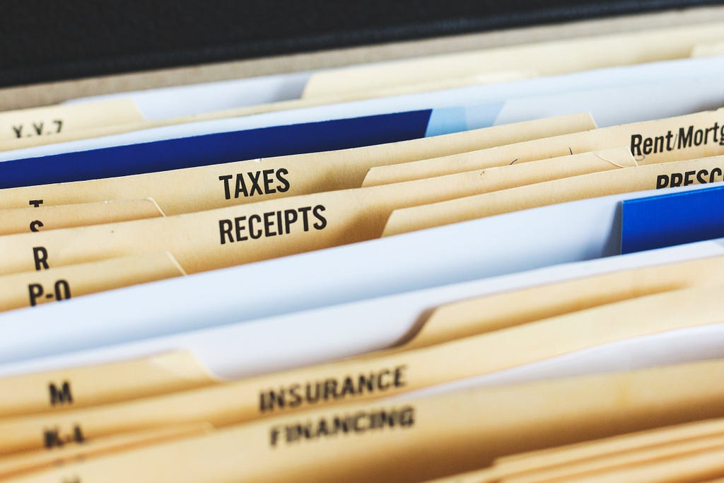 a set of file folders in a box or drawer with labels such as “Taxes”, “Receipts”, “Insurance”, and “Financing”