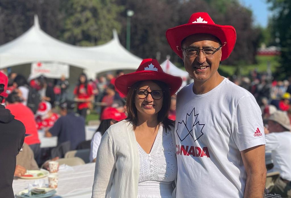 Amarjeet Sohi and his wife, Sarbjeet in red cowboy hats on a sunny Canada Day.