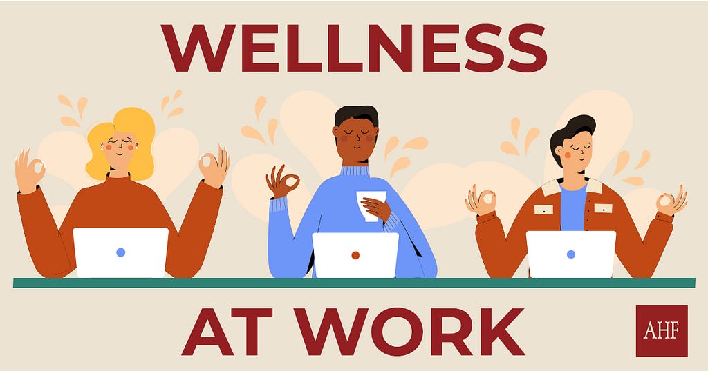 Cartoon image of three professionals at their desks with laptops open. Captioned “Wellness at work”