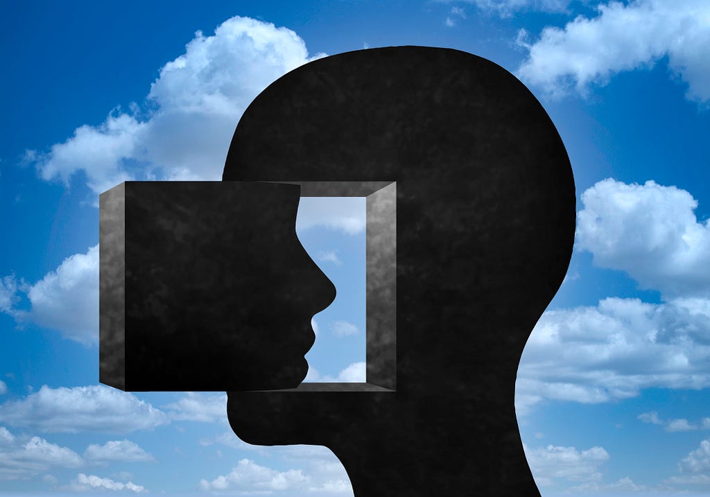 A silhouette of a human head against a cloudy sky.