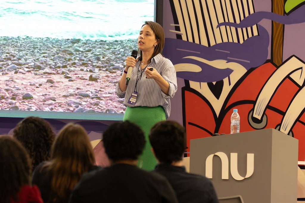 Woman wearing a blue shirt and green skirt, speaking into a microphone at a conference