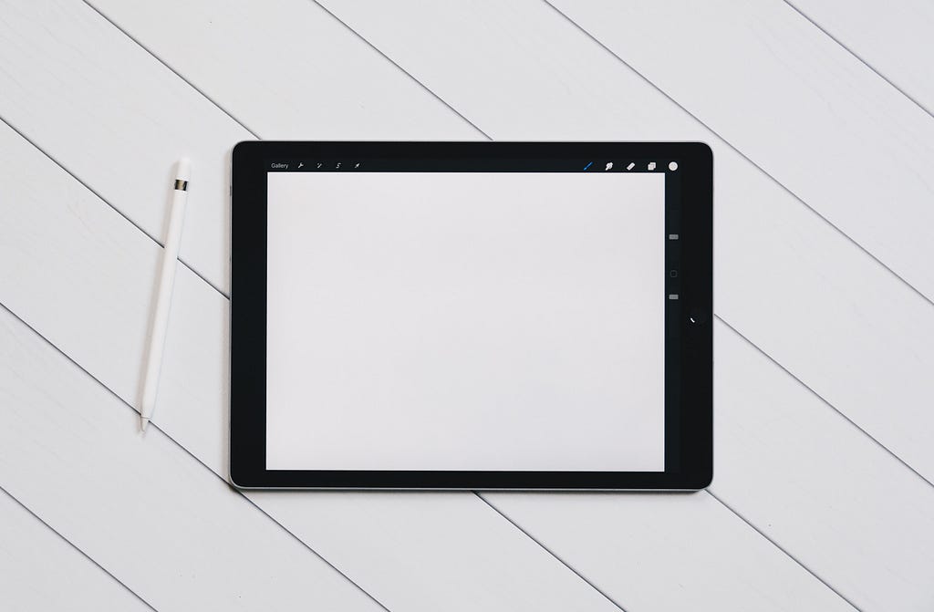 A tablet with blank screen and an apple pencil next to it.