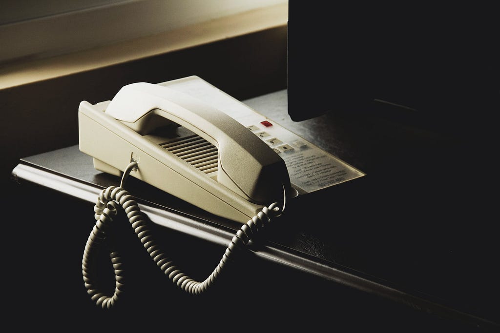 An office phone perched on the corner of a business desk