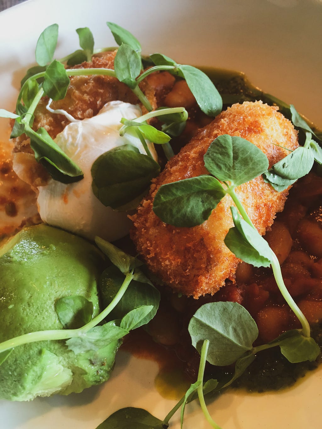 Cheese croquettes with poached eggs and avocado on sourdough toast. A delicious breakfast at a Melbourne cafe.