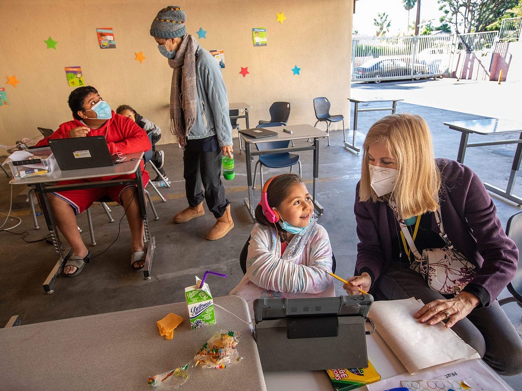 Volunteers help students at a learning pod for homeless children in California.