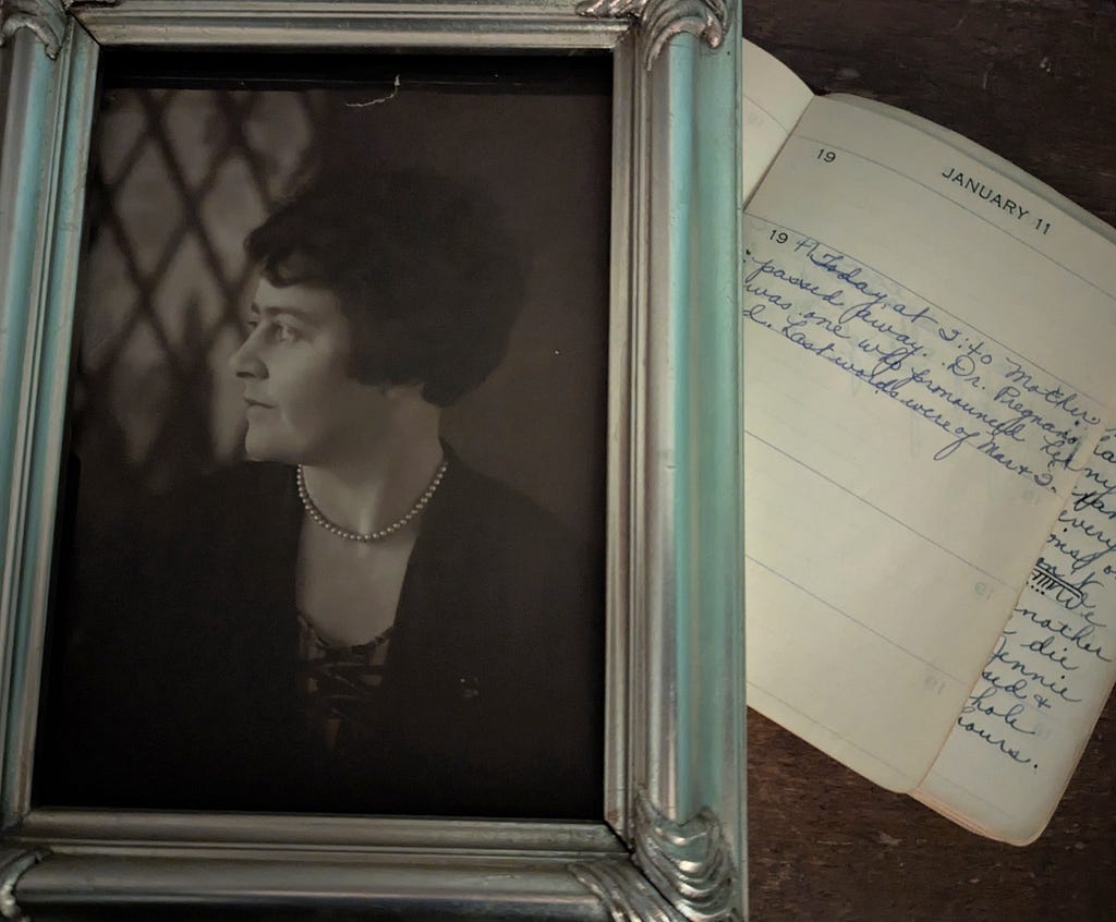 Framed sepia photo of a woman from the 20s, next to an open diary