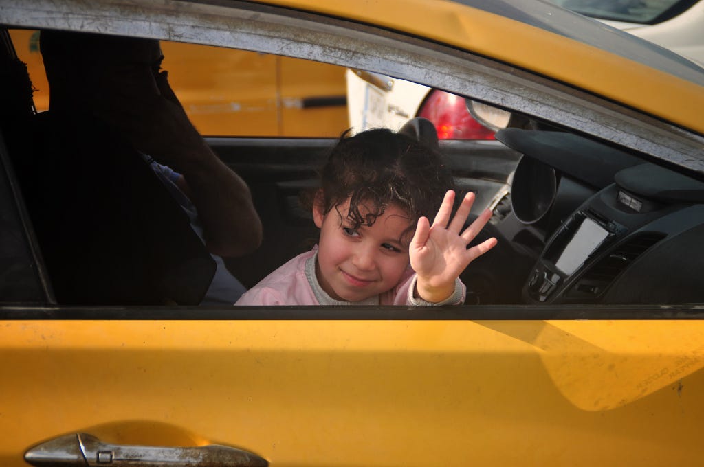 Little Iraqi girl waving out of car window in the streets of Baghdad