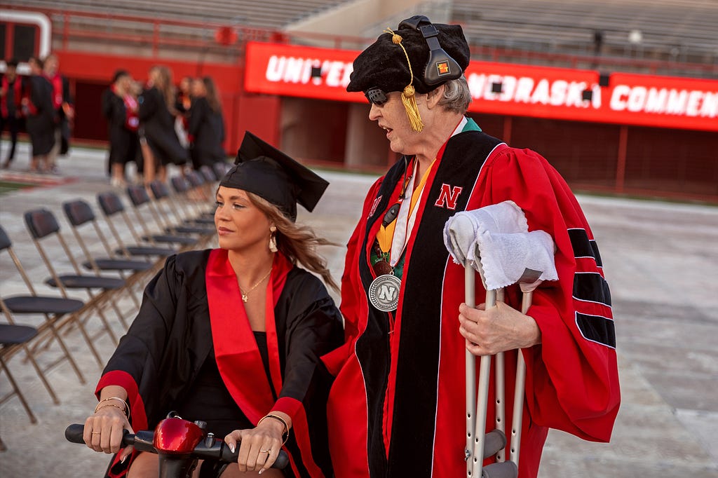 Vanessa Gorman escorts a student needing crutches to their seat before undergraduate commencement