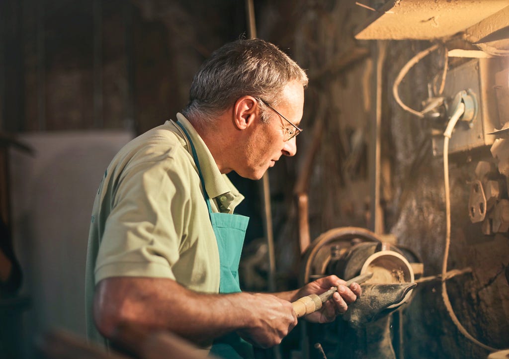 Senior male turner working on lathe machine in workshop