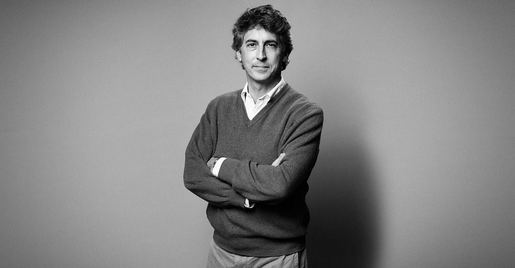 A black-and-white picture of Alexander Payne standing with his arms crossed.