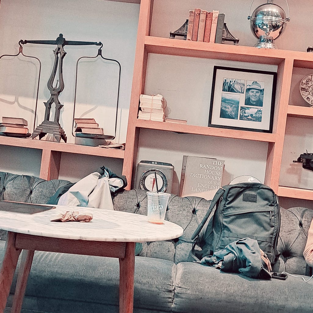 Picture shows a coffee shop with a backpack on a sofa and decorative items on shelves.