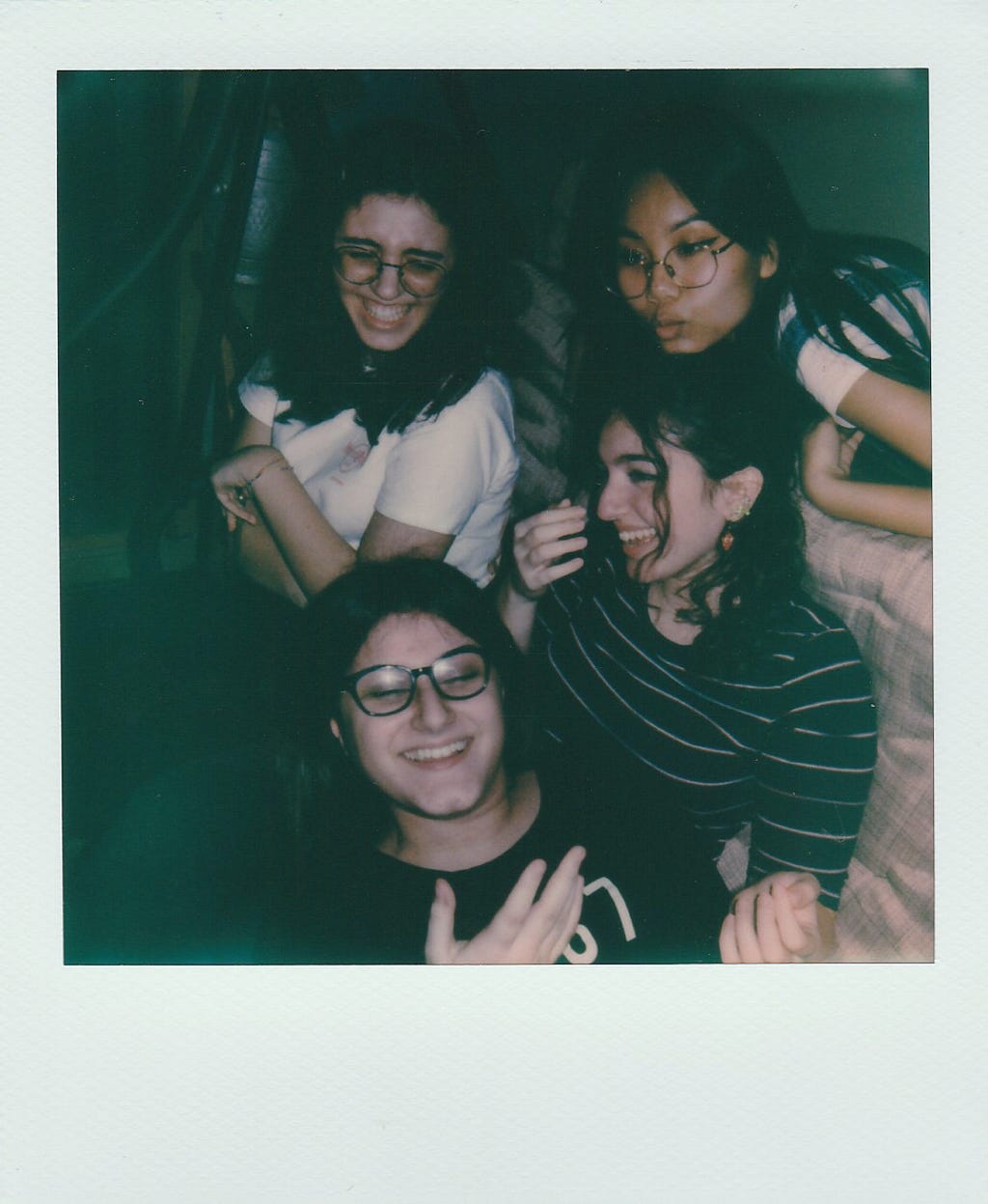 A group of girls smiling in a candid shot on a polaroid.