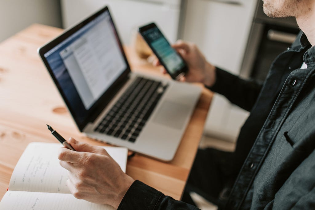 A man with a laptop and smartphone sitting at a desk