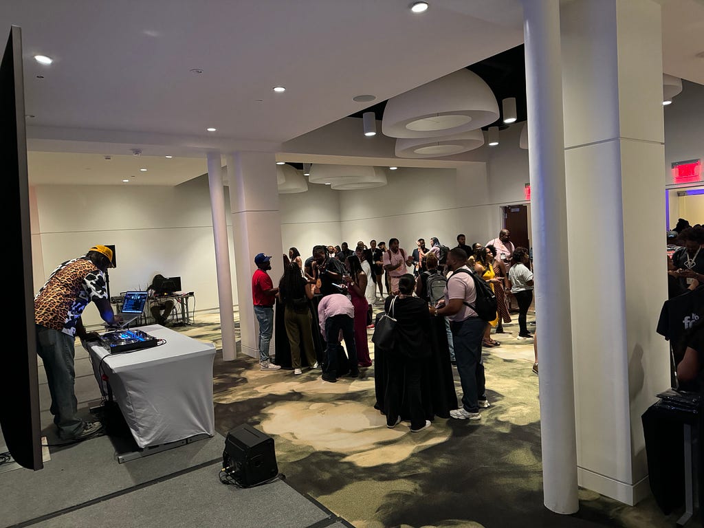 A DJ performing in front of a crowd at a hotel happy hour event.