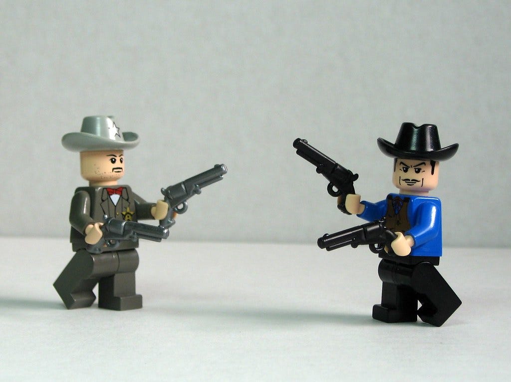 A photo of two Lego characters. They are wearing old wild west costumes and holding two toy guns each.
