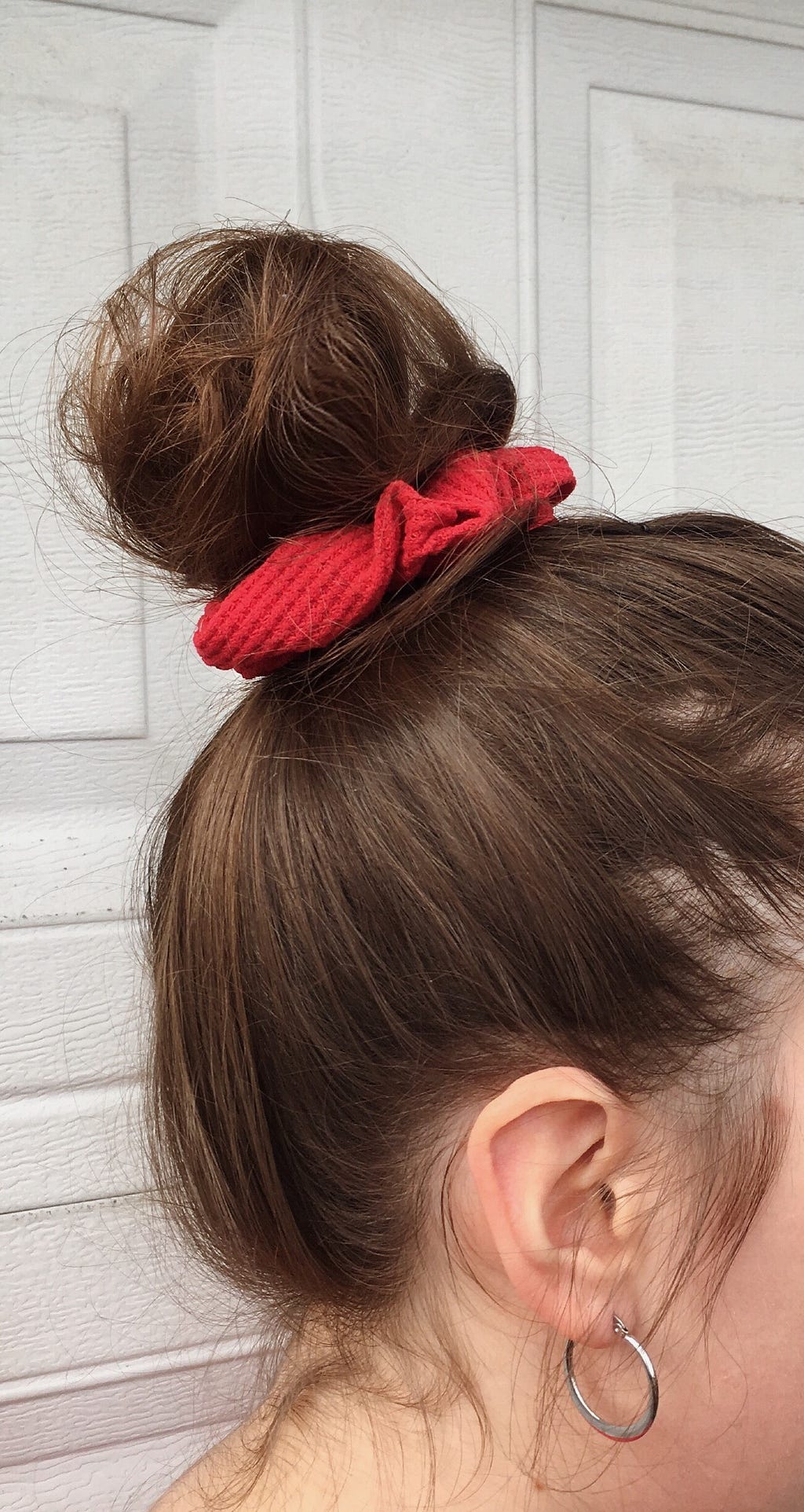 My brown hair up in a bun with a red scrunchie wrapped around it.