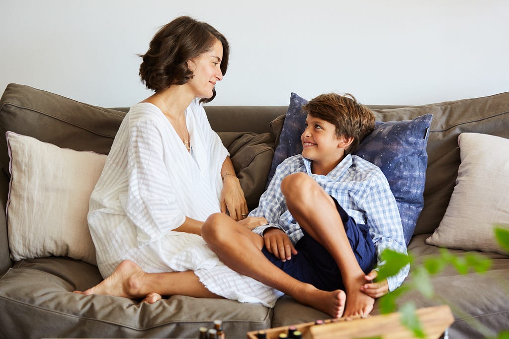 Image of Elena Brower and her son seated on the couch, looking at one another, 2018.