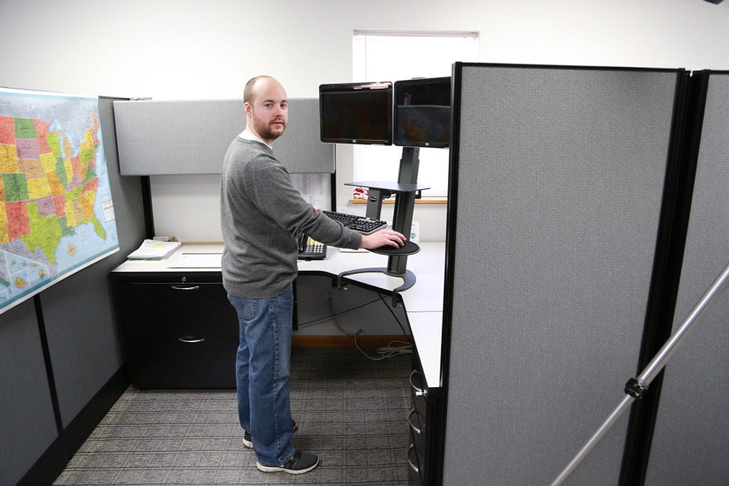 A man standing in front of a computer in an office