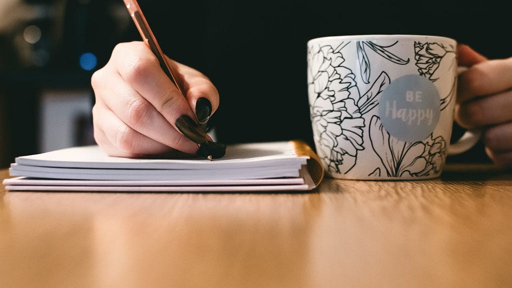 picture of a hand writeing and a coffe mug