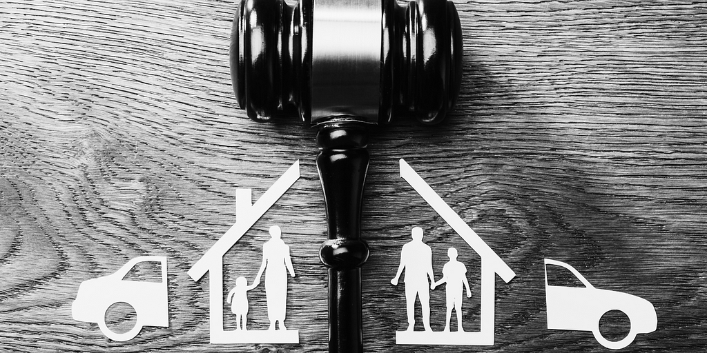 Image of a gavel dividing a paper cutout of a family, car, and house into two parts.