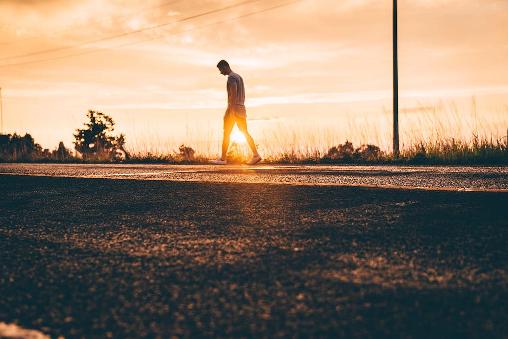 Walking along a stretch of road, by the sunset.