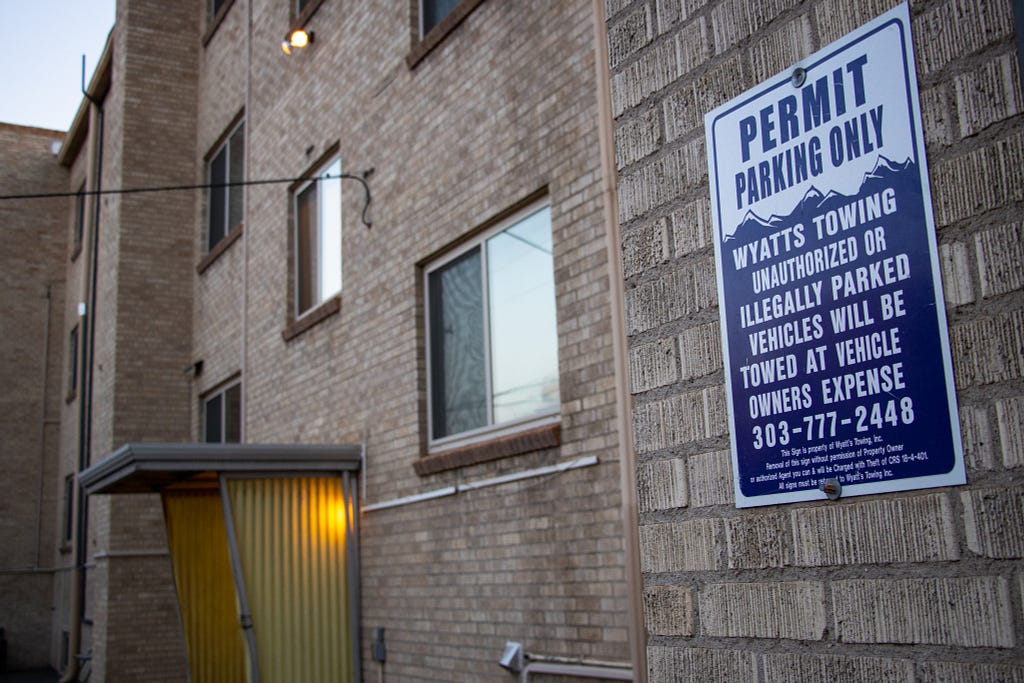 A Wyatts Towing sign mounted to the side of an apartment building in Denver