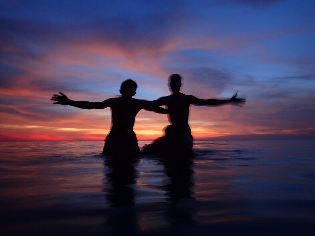 4 traveler’s silhouettes at a pink sunset in Koh Rong island in Cambodia