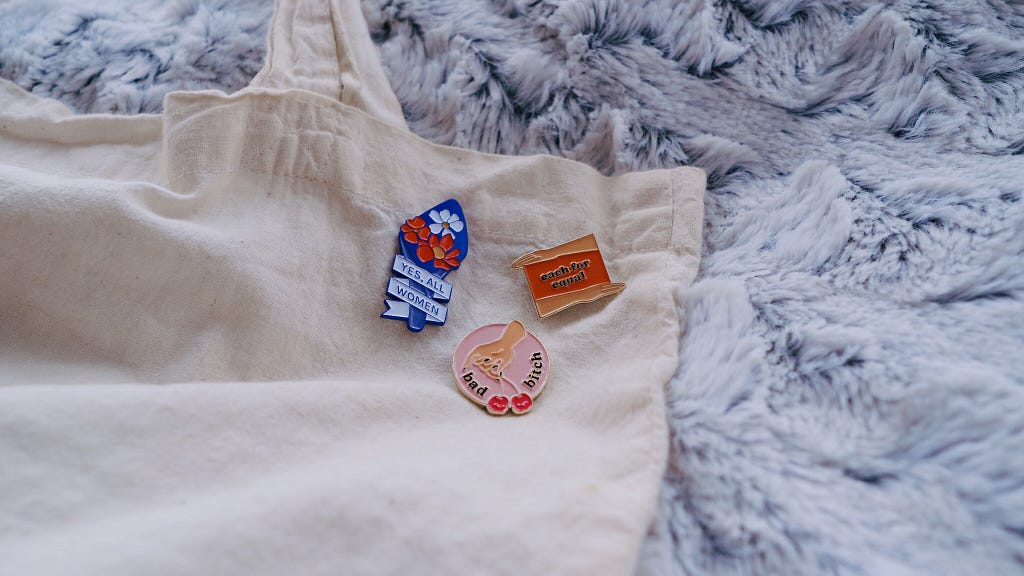 Picture of three enamel pins on a tote bag