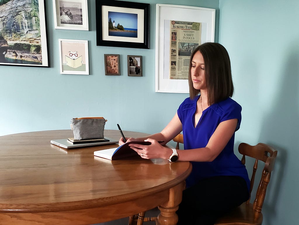 Woman sitting at her dining room table, writing in a notebook.