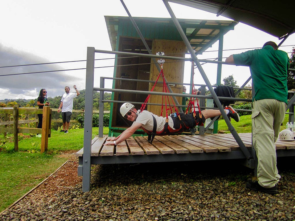 a guy hanging from a zip-line in a tropical climate