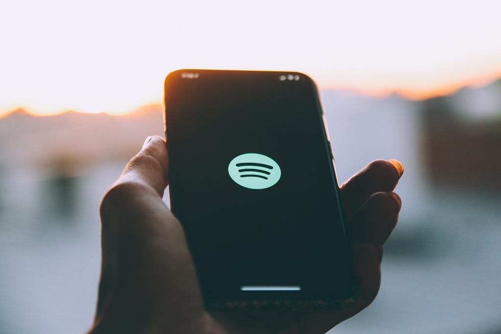 Hand holding a phone with Spotify logo onscreen