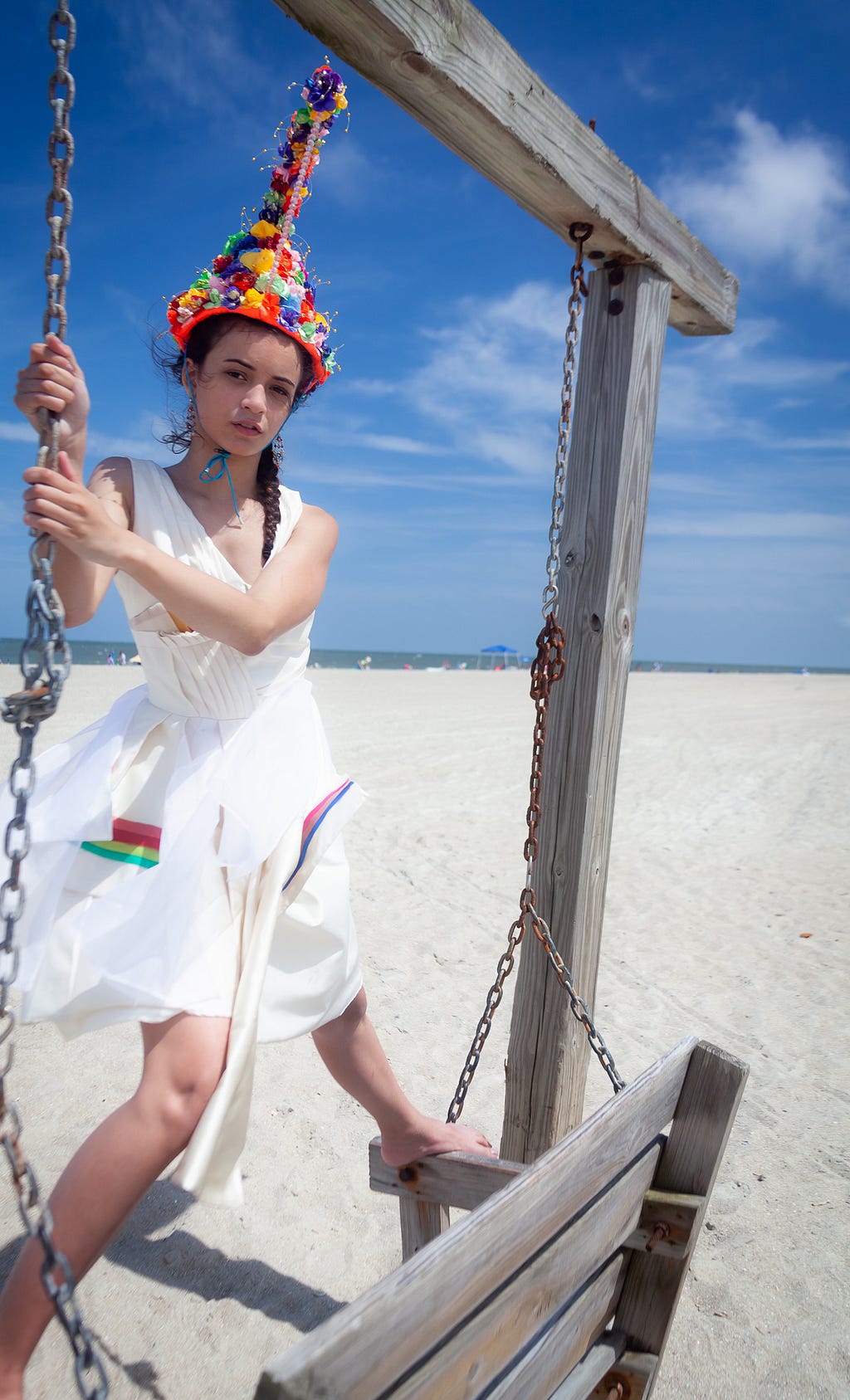 Girl modeling fashion-forward hat and dress on the beach