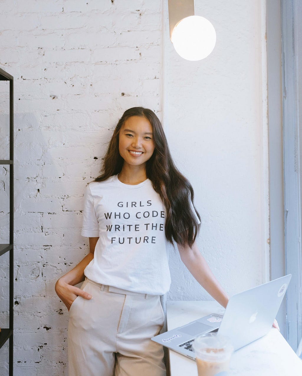 This picture features Marizza wearing a white t-shirt which says — “Girls who code write the future”