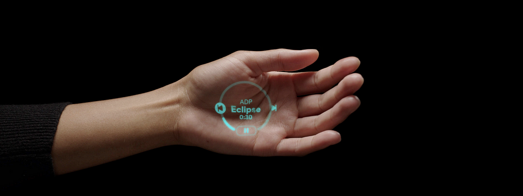 Foto da projeção a laser gerada pelo AI PIN na palma da mão, mostrando a informação de um player de música e seus principais comandos.