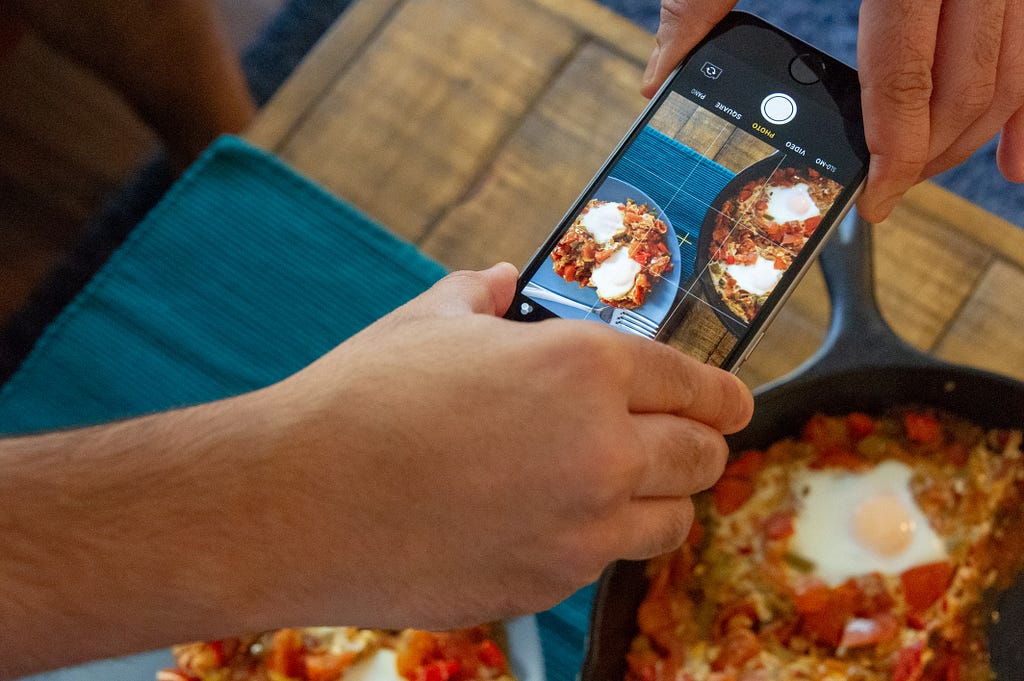 Someone is taking a photo of a cooked meal with their mobile phone