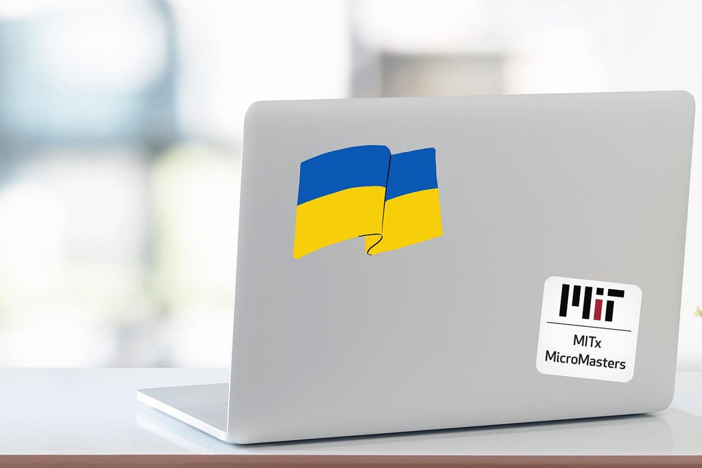 Photo of an open laptop with stickers of the Ukrainian flag and MITx MicroMasters logo.