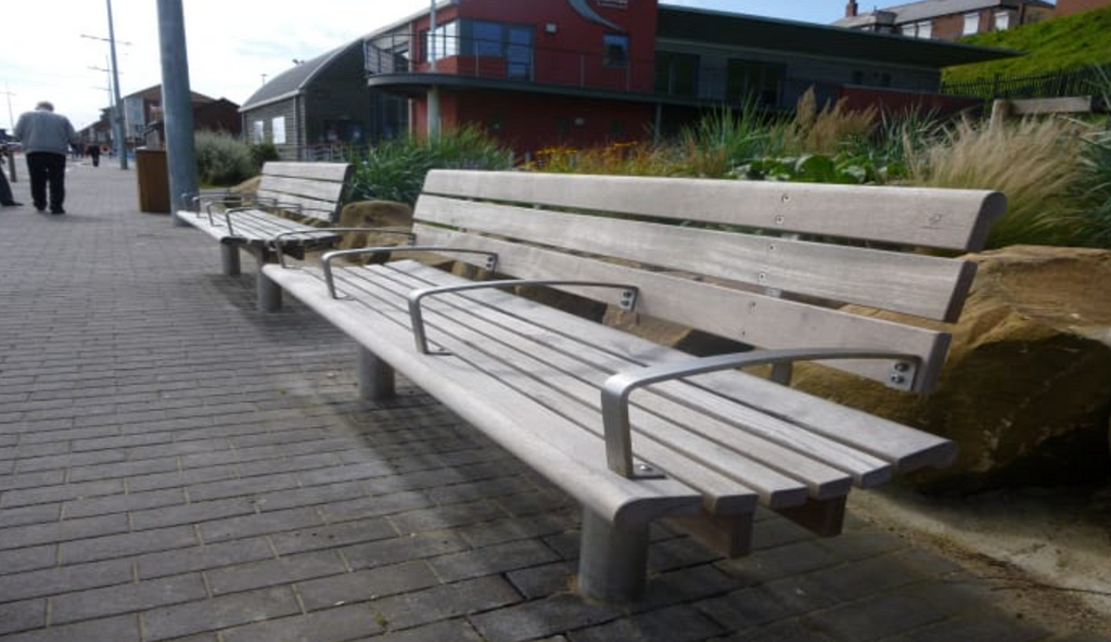 Public wooden bench with 4 armrests to deter sleeping