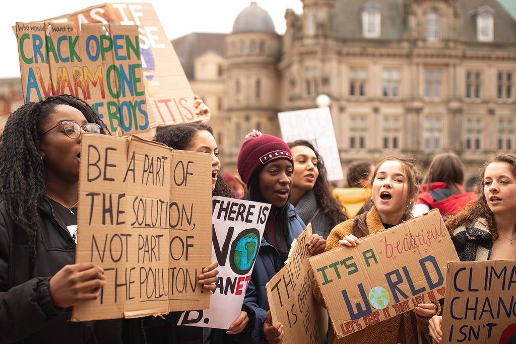 Young climate protestors hold signs with climate slogans