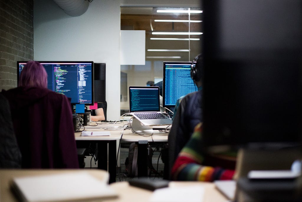 Dos desarrolladores en frente de monitores, leyendo código