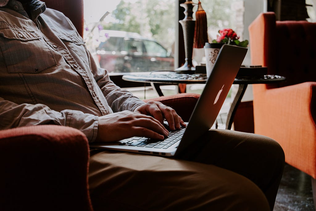 A man sitting in a chair with a laptop on his lap