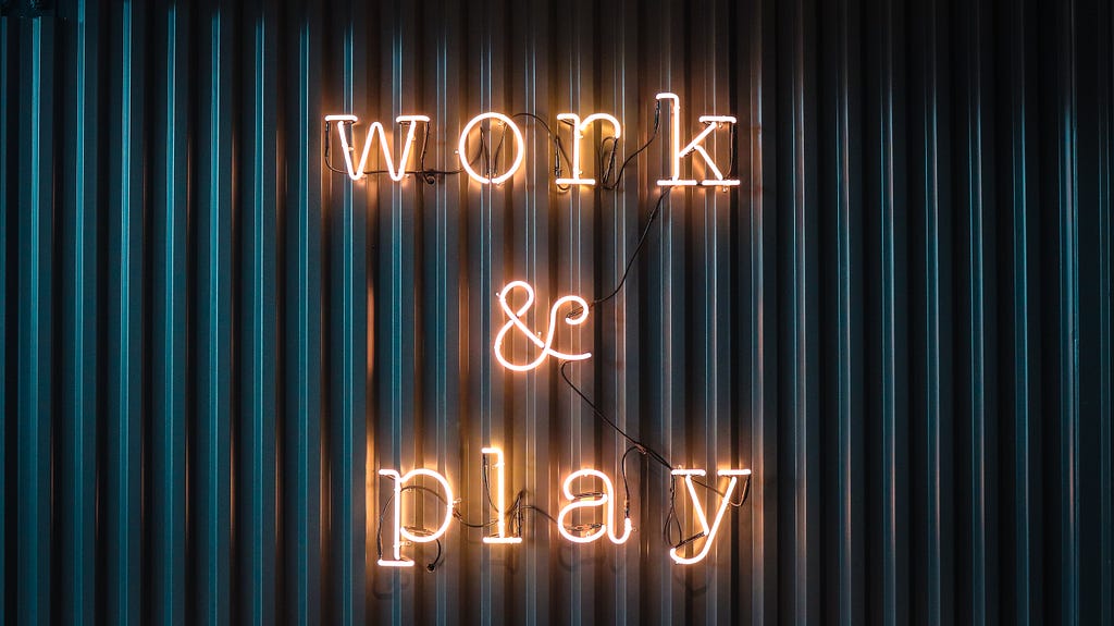 A neon sign that says “Work and Play”