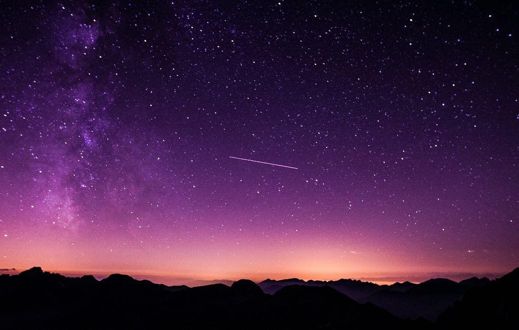 A shooting star against a purple sky and beyond, the universe