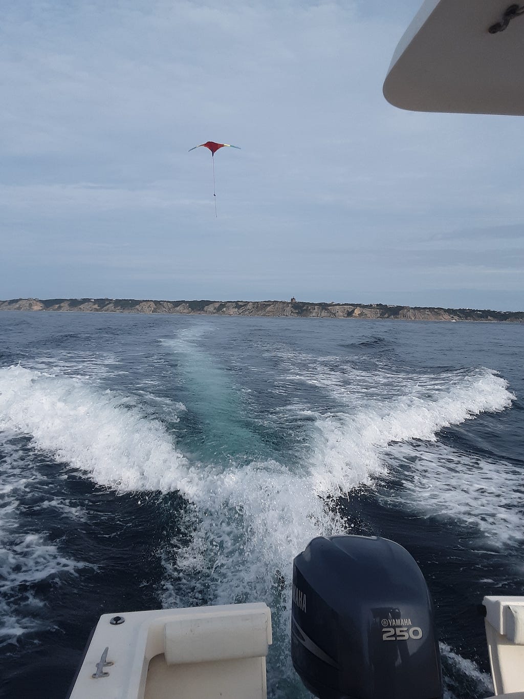 A kite rising up in the air behind a motorboat