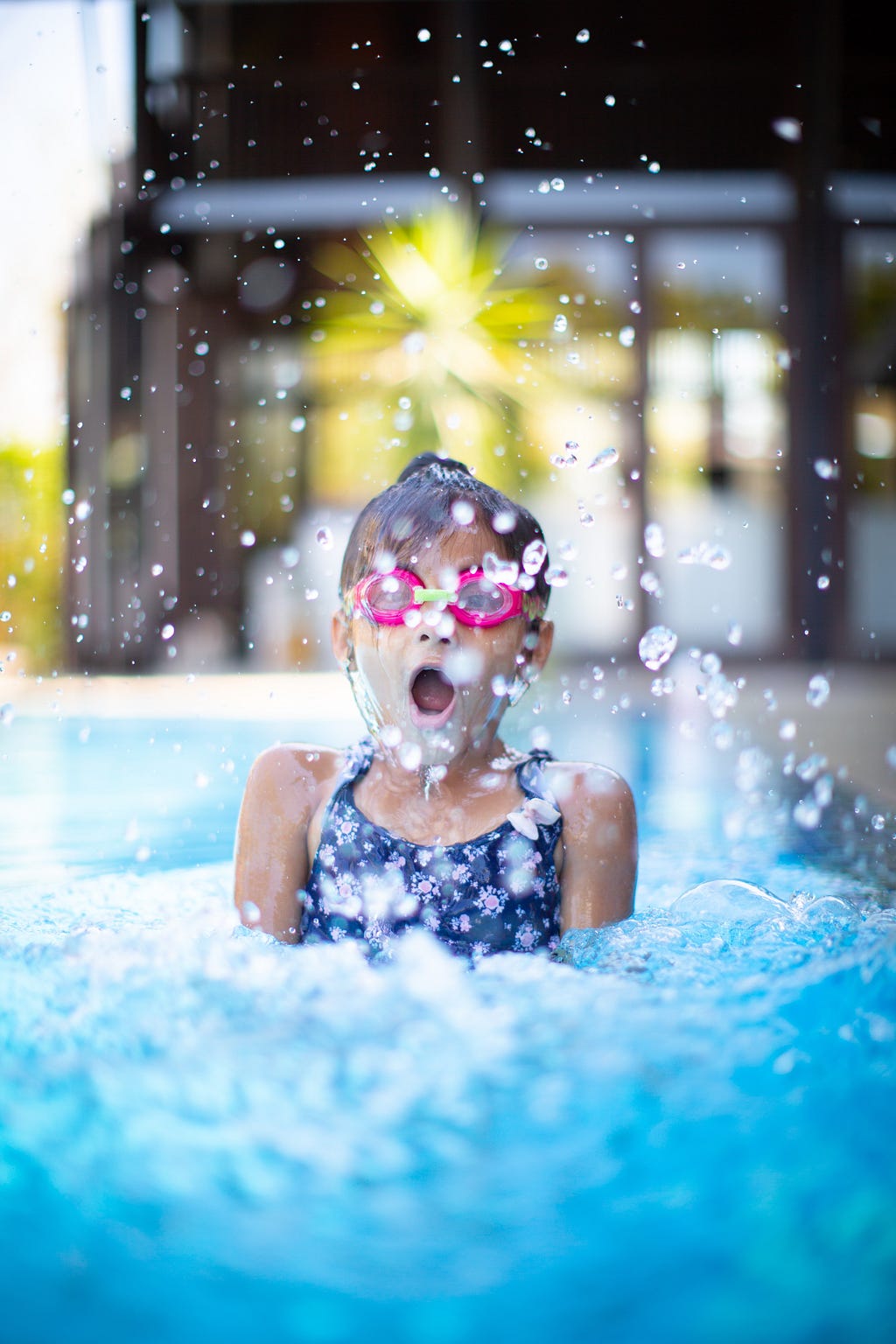 A young girl splashing in a pool.