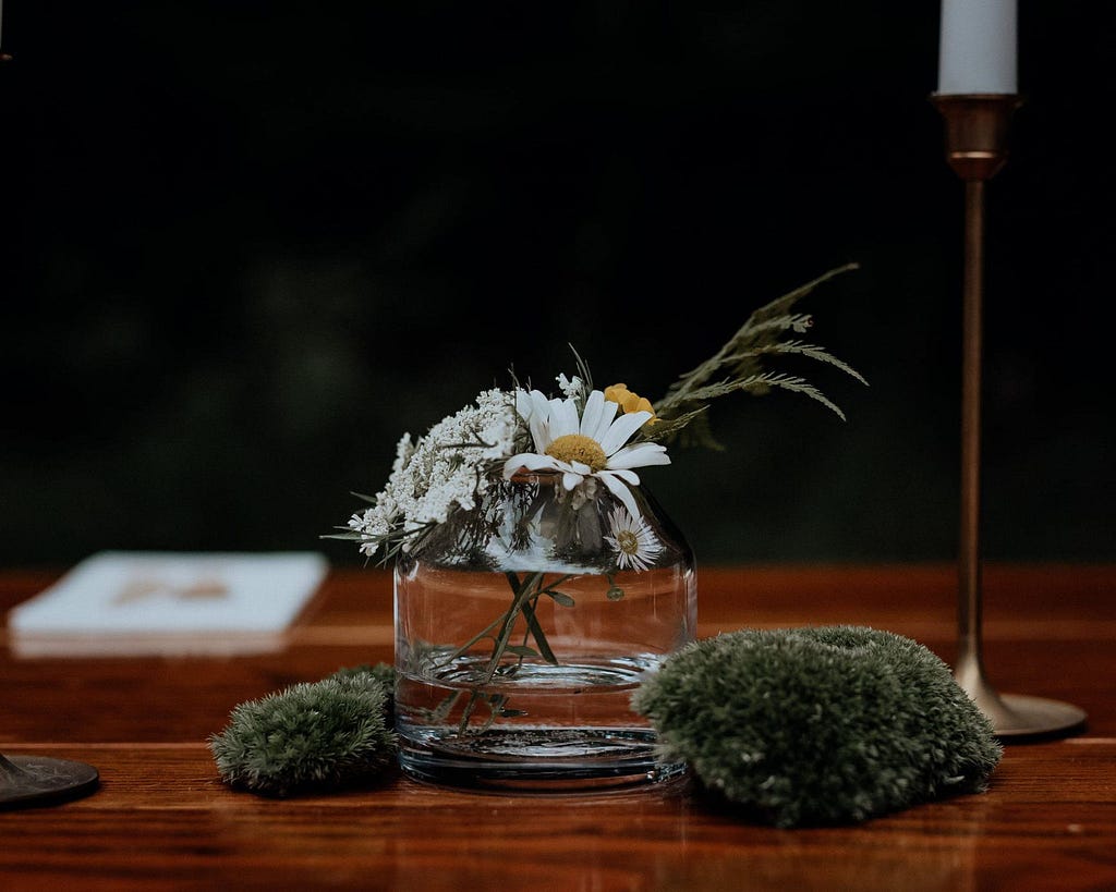 A small wedding centerpiece of foraged flowers and mosses.