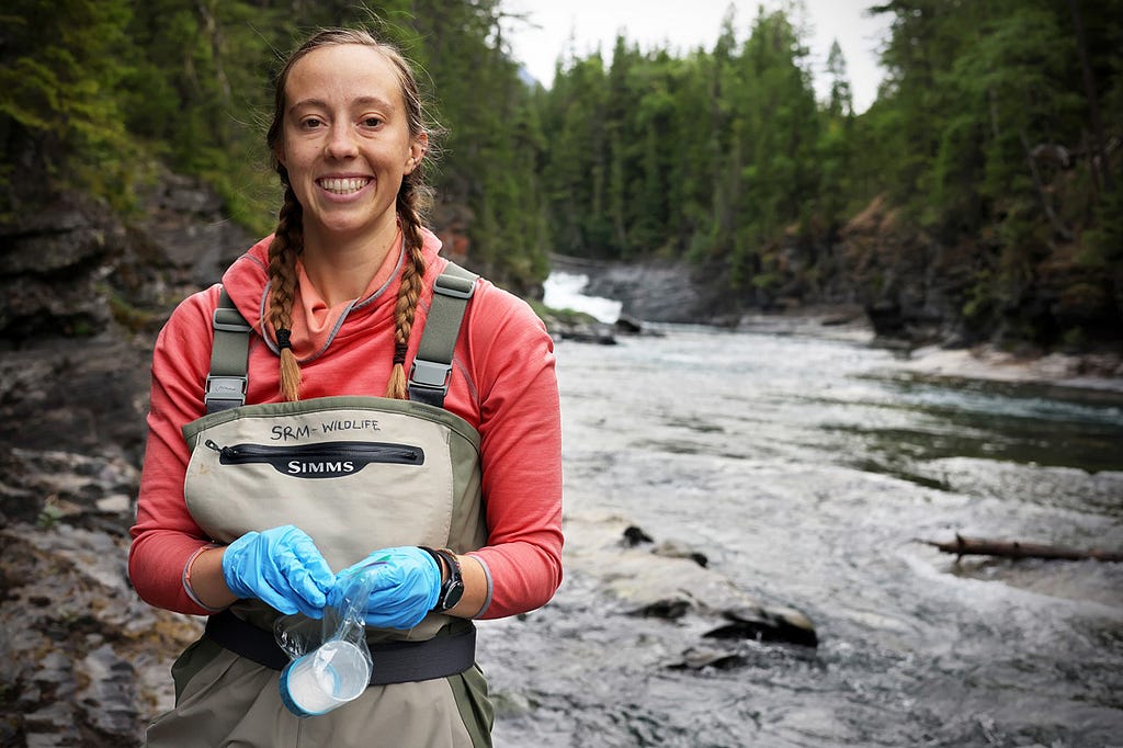 Holli Holmes poses next to a river in waders.