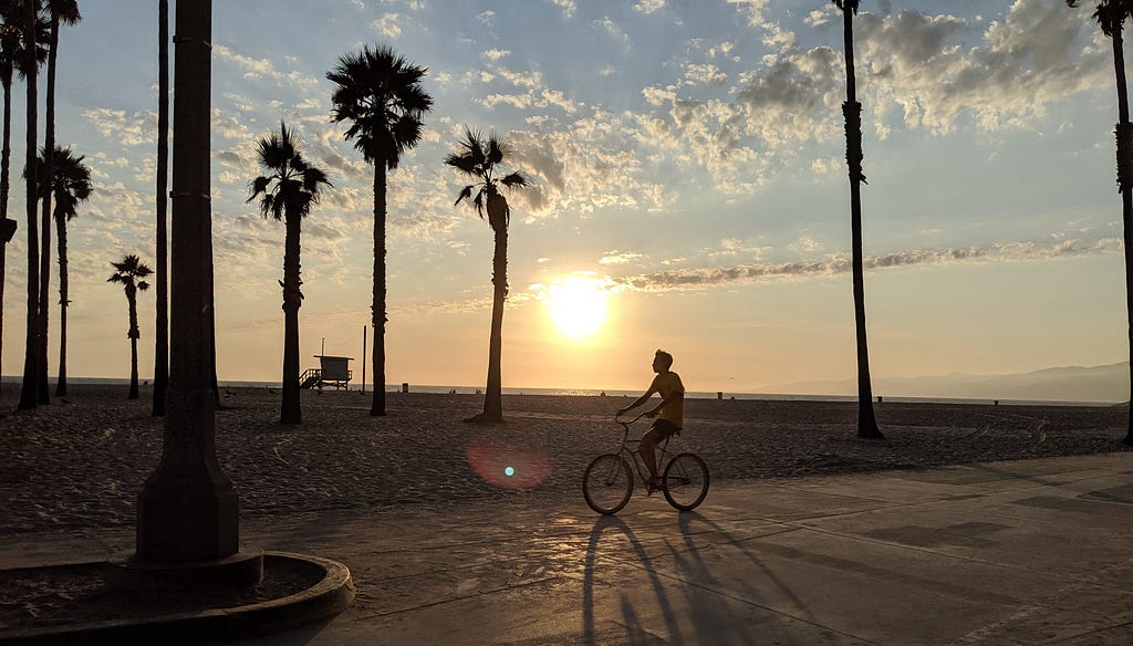 Sunset on Venice Beach with a man riding a bicycle.