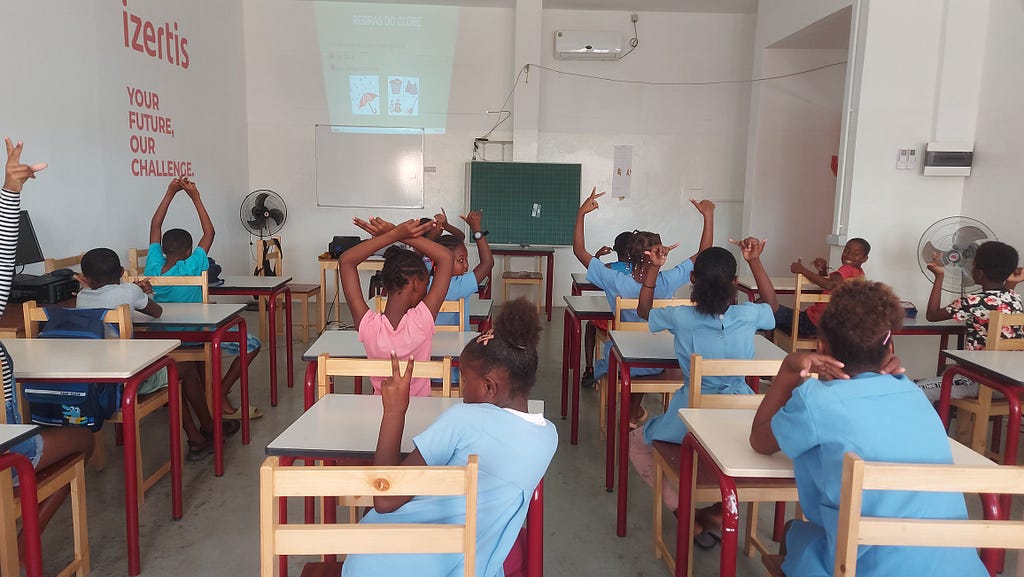 A photograph of children sitting at desks in a classroom.
